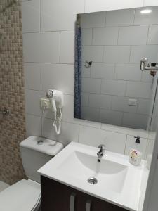 une salle de bain avec un lavabo, des toilettes et un miroir dans l'établissement Vista Puerto Arguineguín Sea View, à Playa de Arguineguín