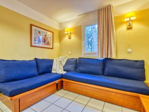 a blue couch in a room with a window at Apartment Les Grands Pins-3 by Interhome in Carcans
