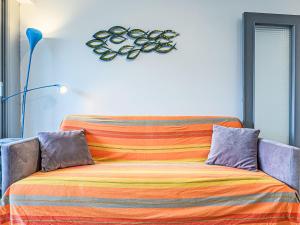 a bed with a colorful blanket and a clock on the wall at Apartment Le Zal-4 by Interhome in Quiberon
