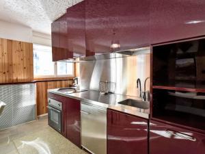 een grote keuken met roestvrijstalen apparatuur en rode kasten bij Apartment -1 by Interhome in Madesimo +25 foto's