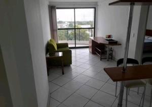 a living room with a couch and a desk and a window at Flat Confortável in Campos dos Goytacazes