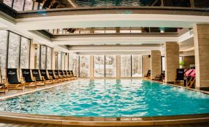a large swimming pool in a building with chairs at Gold Apartments Kopaonik in Kopaonik