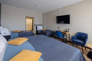a hotel room with two beds and a desk and a tv at Meyer Hamina in Hamina