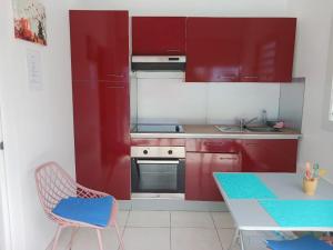 a kitchen with red cabinets and a table and chairs at Refuge et Bellevue in Sainte-Luce