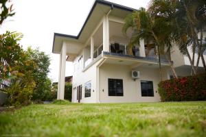 a white house with a balcony and palm trees at Tropical Villa Rainville in Paramaribo