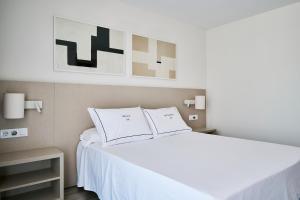 a bedroom with a white bed with two pillows at Helios Benidorm in Benidorm