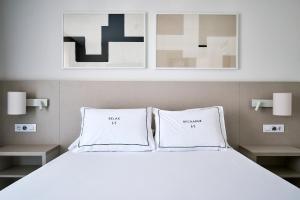 a bedroom with a white bed with two white pillows at Helios Benidorm in Benidorm