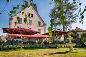 a restaurant with tables and umbrellas in front of a building at Hôtel Le Vouglans - Restaurant La Valouse in Orgelet