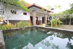 une villa avec une piscine en face d'une maison dans l'établissement Graha Rusni, à Ubud