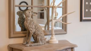 a statue of a dog sitting on a table in front of a mirror at Antelope Cottage in Northleach +18 photos