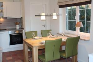 una cucina con tavolo in legno e sedie verdi di LITZKOW 11208 a Morsum Altre 3 foto