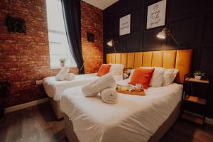 zwei Betten in einem Hotelzimmer mit weißen und orangefarbenen Kissen in der Unterkunft Luxury City Apartment-Sleeps 4-Sofa Bed- Free Parking in Nottingham + 10 Fotos