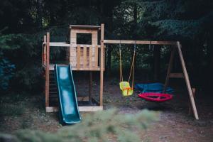 a playground with two swings and a slide at Wolny Las in Ławki