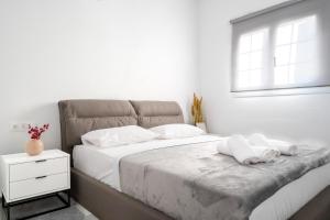 a bedroom with a bed with white sheets and a window at Noho Villas @ Sunlit house Paros in Nea Cryssi Akti