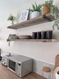 a kitchen with wooden shelves and a microwave at Boho Bay Two - Seaside Escape in Cullercoats