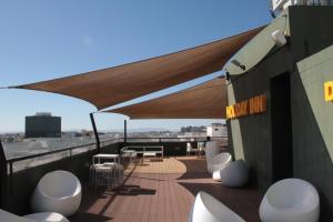 a balcony with white chairs and tables on a roof at Holiday Inn Lisbon by IHG in Lisbon