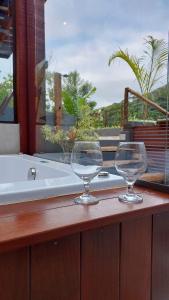 two wine glasses sitting on a counter next to a tub at Casa da Bella - 1,5km do centro de Lumiar in Nova Friburgo +62 photos