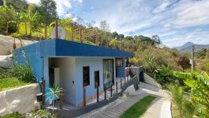 a blue and white building with a clock on a hill at Casa da Bella - 1,5km do centro de Lumiar in Nova Friburgo