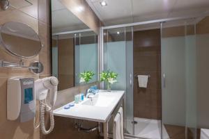 a bathroom with a sink and a shower with a mirror at Helios Benidorm in Benidorm