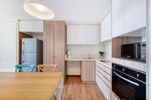 una cucina con mobili bianchi e un tavolo di legno di Oceana Suite - Frente al Mar a Concón