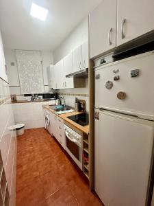 une cuisine avec des armoires blanches et un réfrigérateur blanc dans l'établissement El Botxito, à Bilbao