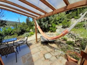 a hammock on a patio with a table and chairs at A tiny sea home in the wilderness in Vis