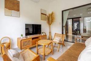 un salon avec une télévision, une table et des chaises dans l'établissement Gemstones Villa, à Seminyak