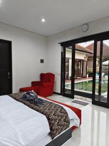 ein Schlafzimmer mit einem Bett und einem roten Stuhl in der Unterkunft Two Bed Room Villa with Pool in Jimbaran