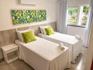Una habitación de hotel con dos camas y una ventana. en Flamingo - 4 suite -15 gasten - Arraial d' Ajuda, en Porto Seguro 66 fotos más