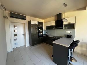 a kitchen with black cabinets and a white tile floor at Imperial Apartman in Győr