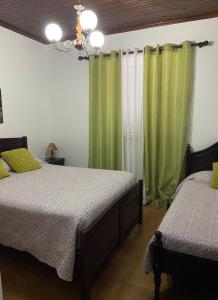 une chambre avec deux lits et des rideaux verts dans l'établissement Val's Place, à Praia da Vitória