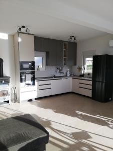a kitchen with white cabinets and a black refrigerator at Kuća za podmor Olea in Nečujam