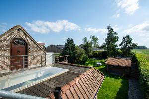 a hot tub on the deck of a house at Au Jardin du Trieu in Pecq