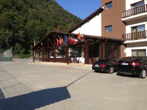 ein Gebäude mit Flaggen und Autos auf einem Parkplatz in der Unterkunft Hotel Class in Brezoi