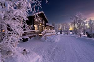 a house covered in snow next to a snow covered tree at Nivunki Village in Muonio