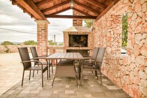 eine Terrasse mit einem Tisch und Stühlen sowie einem Steinkamin in der Unterkunft Luxury Villa Kras in Dobrinj