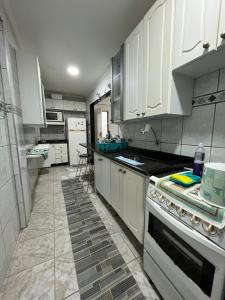 a kitchen with white cabinets and a stove top oven at Apartamento aconchegante na Praia do Pereque-Açu in Ubatuba +6 photos