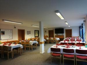 ein Konferenzraum mit Tischen und Stühlen und einer Leinwand in der Unterkunft Gästehaus Bleckmar in Bergen