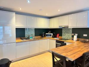 a kitchen with white cabinets and a wooden table at Centrally located apartment in Duke Street- free parking- two bathrooms in Liverpool