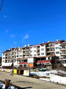 a large white apartment building with snow in front of it at Tryavna Lake Apartment in Tryavna +4 photos