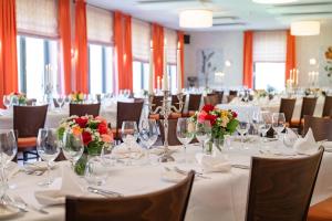 a banquet room with white tables and chairs with flowers at Landhaus Wern's Mühle in Ottweiler