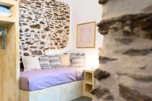 a bed in a room with a stone wall at House on the island in Kithnos