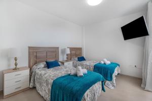 two beds in a bedroom with blue sheets at Villa Atlantico in Candelaria