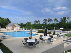 a pool with tables and chairs with umbrellas at Peaceful Retreat on the Intracoastal Waterway! Myrtle Beach - Indoor Pool in Myrtle Beach