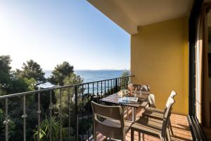 a balcony with a table and chairs and the ocean at La Résidence du Bailli in Rayol-Canadel-sur-Mer