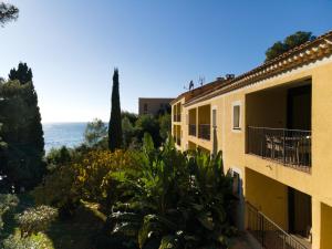 a view of a building with the ocean in the background at La Résidence du Bailli in Rayol-Canadel-sur-Mer