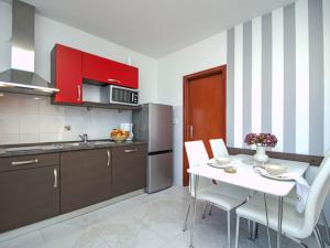 a kitchen with red cabinets and a white table and chairs at Apartment Aquanur-5 by Interhome in Sovlje