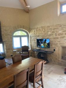 a dining room with a table and a television on a wall at Village house near Uzes in Saint-Siffret