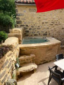 a swimming pool in a stone building with a table and a red umbrella at Village house near Uzes in Saint-Siffret