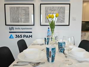a table with plates and glasses and yellow flowers on it at 365PAM - Apartament Bliżej Morza w Gąskach in Gąski